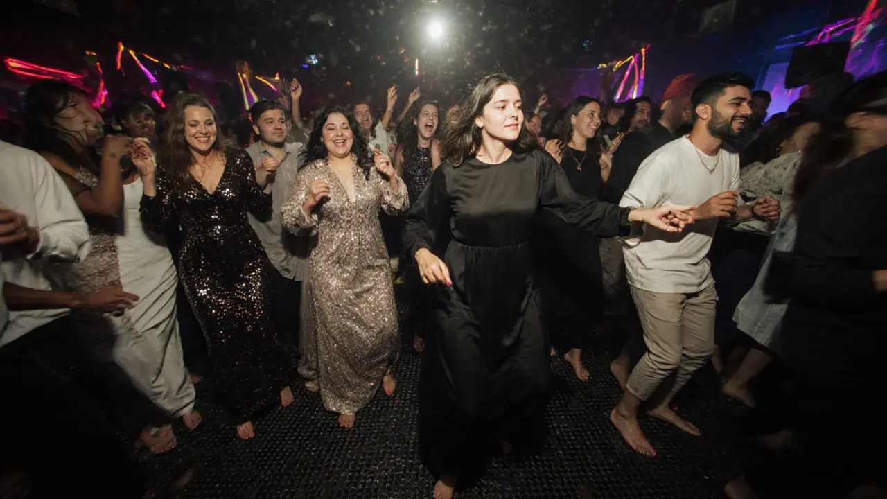 Diverse group of people dancing together in a sleek, logo-free nightclub with ambient lighting.